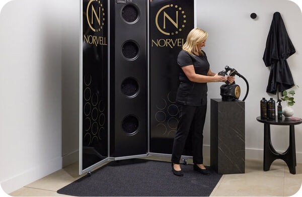 Instructor preparing Norvell equipment for live spray tanning certification in Charlotte, North Carolina