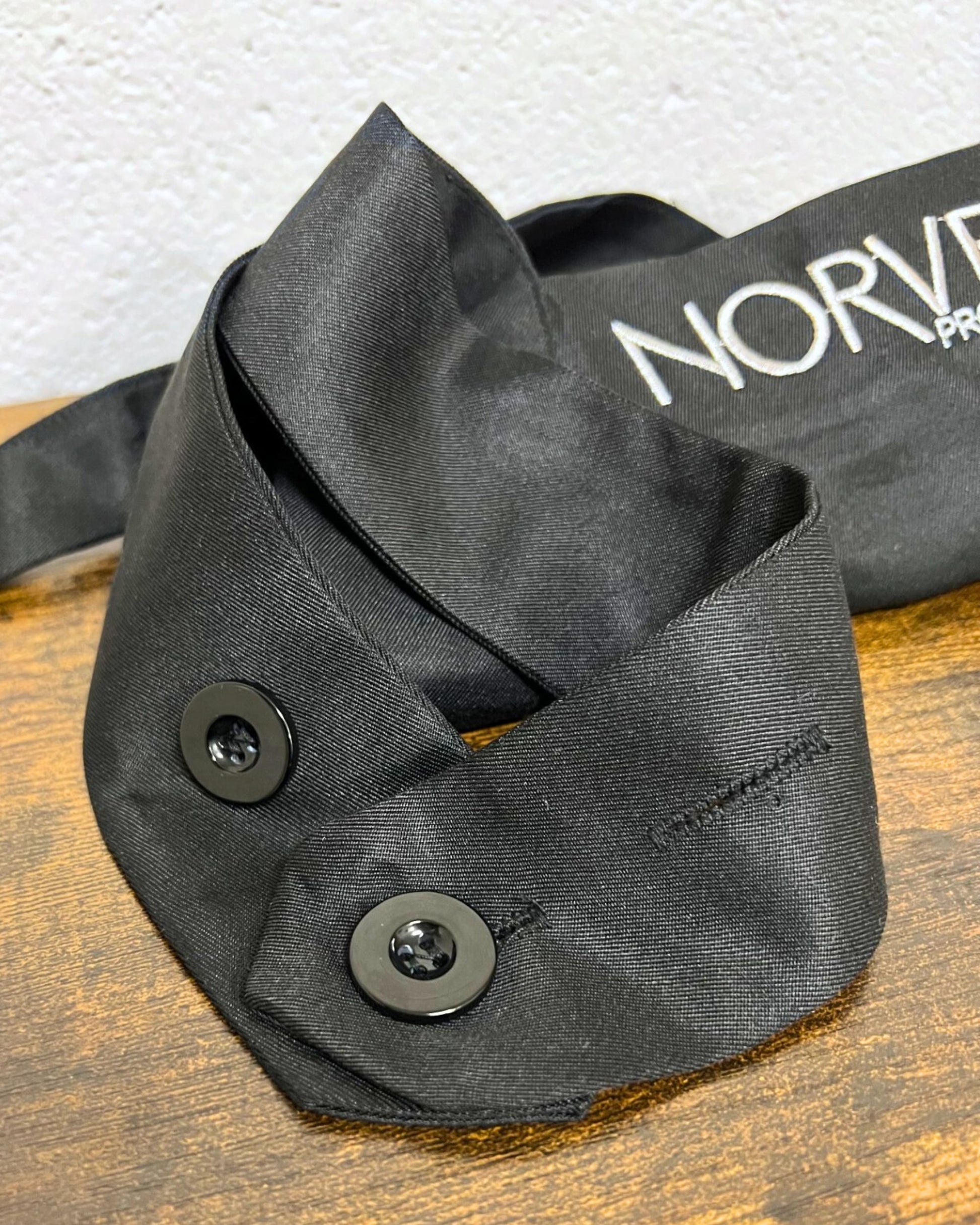 Close up of button closure for the Norvell black apron, on a wooden surface