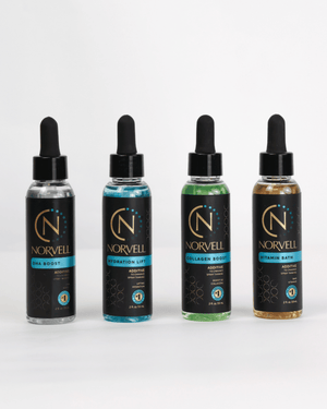 Four Norvell liquid dropper bottles lined up on a white background, showing different additives: DHA Boost, Hydration Lift, Collagen Boost, and Vitamin Bath.