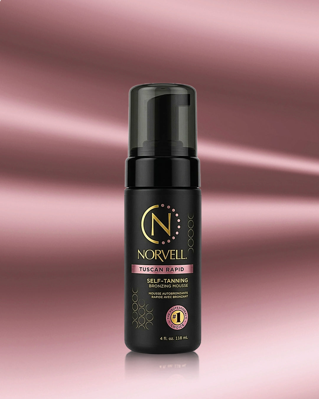 A bottle of Norvell Self-Tanning Mousse in the Tuscan Rapid shade, featuring a black bottle with gold and pink lettering, set against a rose gold gradient background.
