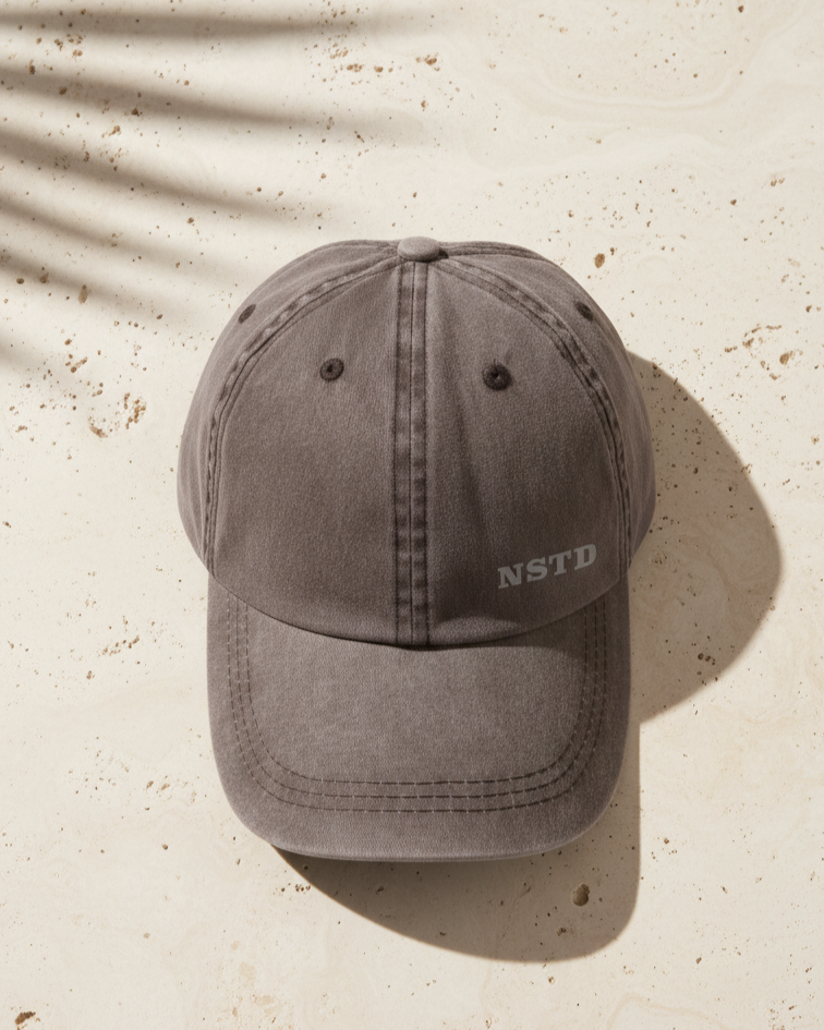 AI Render brown cap with 'NSTD' logo on a beige surface