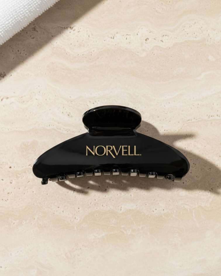 AI Render example Black hair clip with 'Norvell' branding on a beige surface